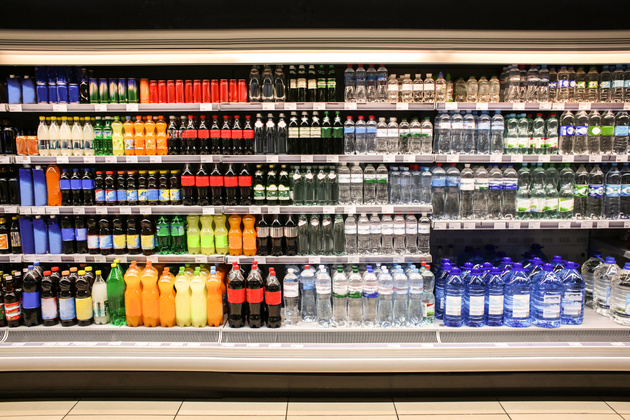 A variety of beverage bottles sit on shelves in a retail store