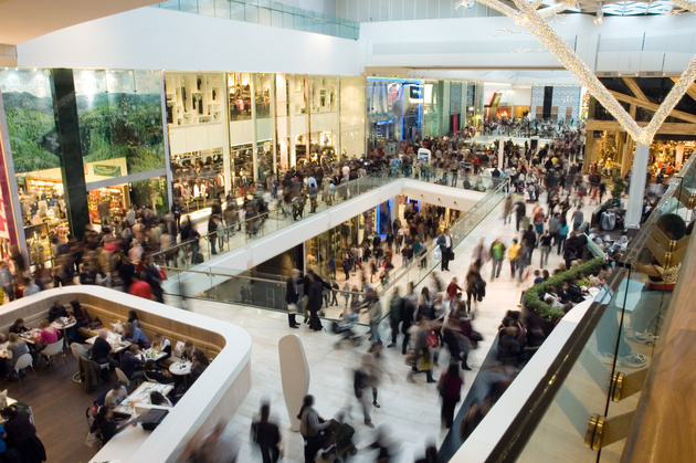 A group of individuals walk through several different floors of a mall,
