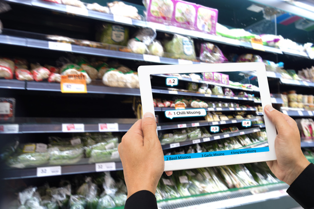 A man holds a device that allows him to see what items are missing from the grocery shelf 